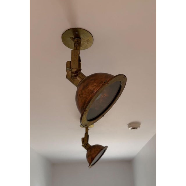 Pair of nautical light fixtures in unlacquered brass finish. Fixtures give a maritime or industrial feel to any space....