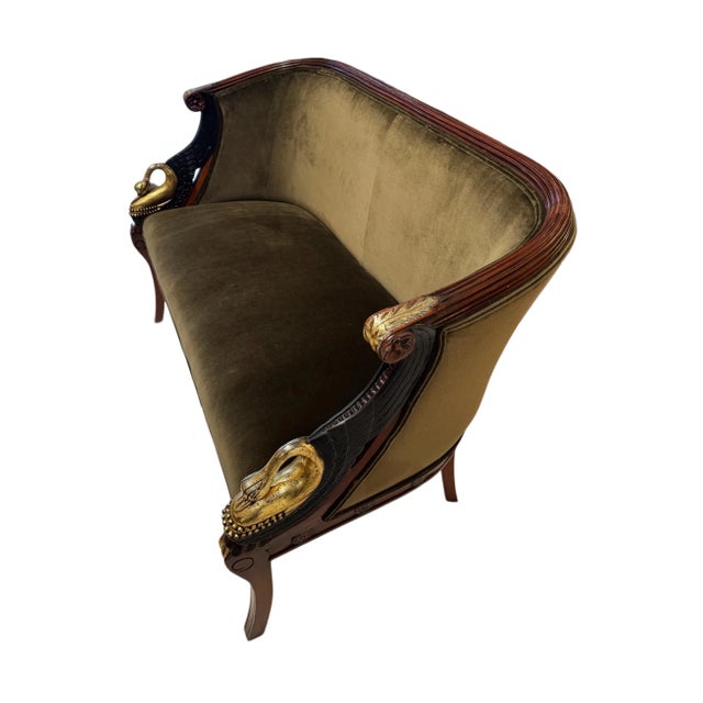 Elegant and sculptural, this vintage Empire-style settee features a finely carved mahogany frame highlighted by gilt and...