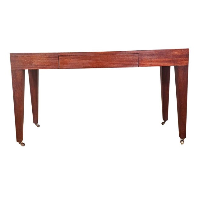 A pair of minimalist midcentury style console tables with tapered legs ending on casters. A single drawer flush to the...