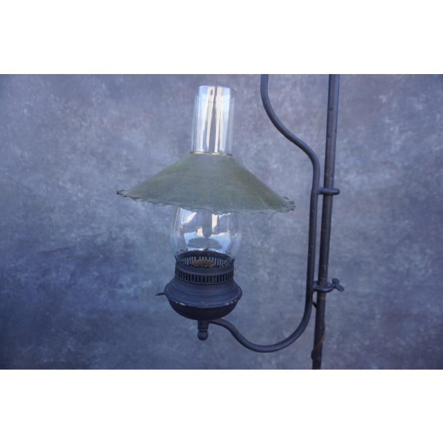 Antique wrought iron floor lamp in the Monterey style, featuring a lantern-form light with glass chimney and metal shade....