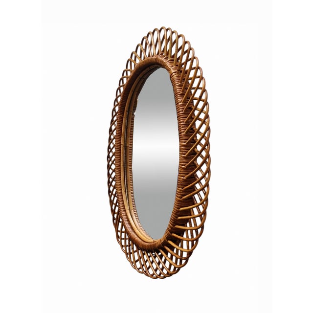 Italian rattan wall mirror (circa 1960s) by Franco Albini. The mirror has a complex weave of rattan in a series of...