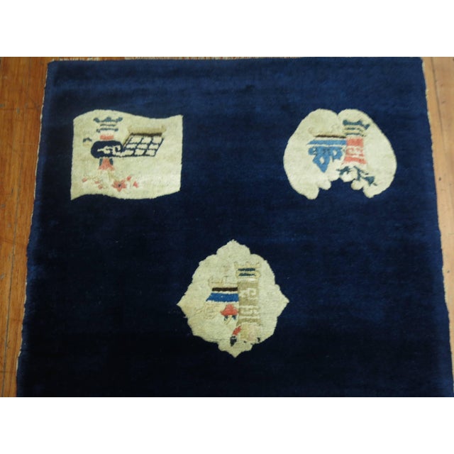A folksy early 20th century Chinese Peking rug featuring eight irregular shaped elemental motifs on a midnight blue...