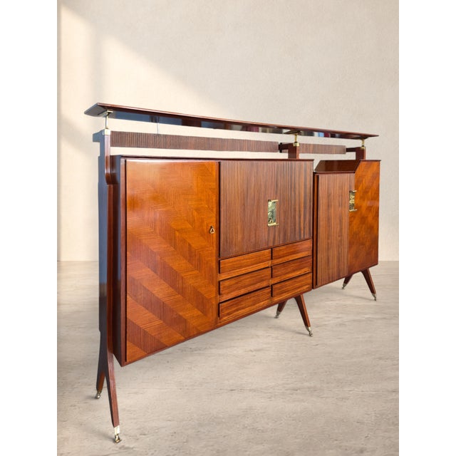 This Italian Mid-Century bar cabinet, produced by La Permanente Mobili Cantù during the 1950s–60s, is defined by an...