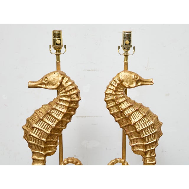 A pair of gilt metal seahorse fragments, transformed into sculptural table lamps and mounted on custom lucite bases. These...