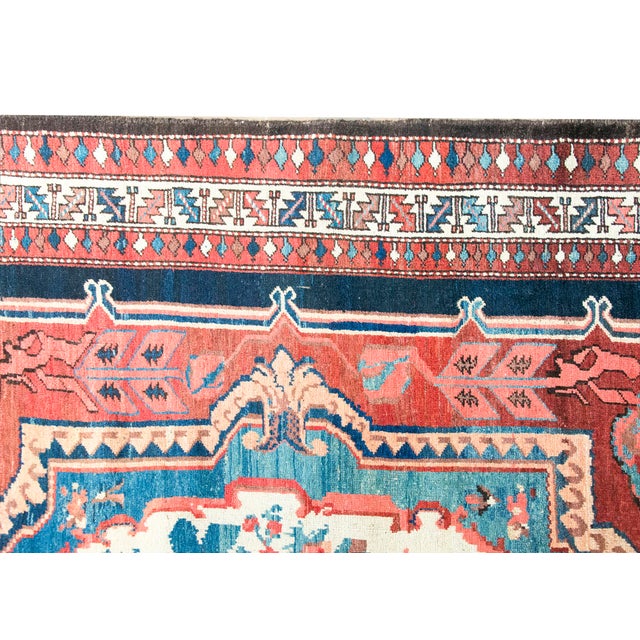 An antique Persian Bakhtiari Saman rug from the 1920s, featuring a striking central floral medallion in red and ivory. The...