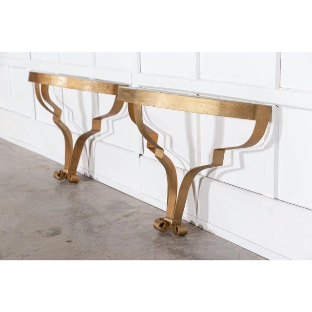 Circa late 20th Century Pair of gilt metal console tables with simulated marble tops from a prominent film and theatre...