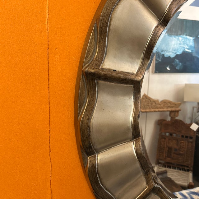 Gorgeous large round wall mirror fabricated of wood painted in gold and silver antique finish. It has a scalloped and...