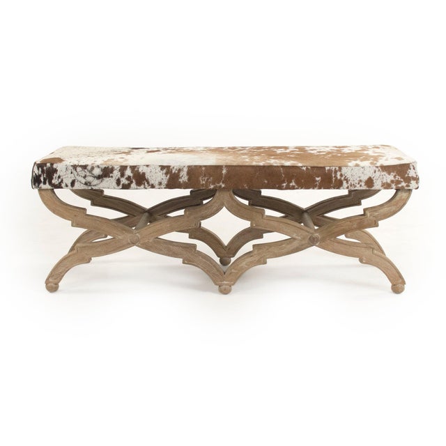 This is a bench featuring a sophisticated design with cowhide upholstery and an oak wood frame. The upholstery showcases a...