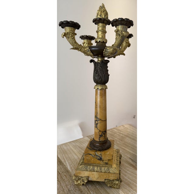 A pair of Charles X or Louis Philippe period patinated bronze and sienna marble five-light candelabra with flame finials,...