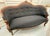 An antique Victorian black and wood loveseat couch. This couch has incredible shape and details and would look amazing...