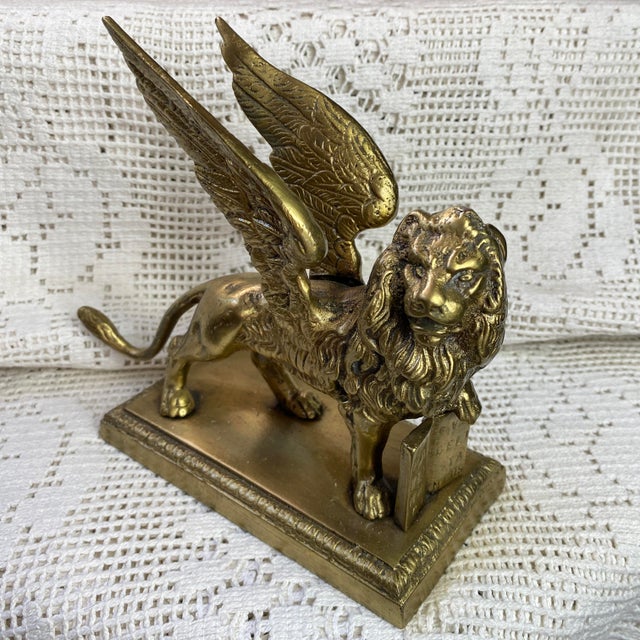 Bronze lion representing the Lion of Saint Mark, the winged symbol of Venice, holding a book, the Gospel, open under its...