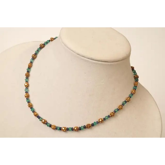 A delicate yet significant 22K gold necklace with faceted blue sapphires and faceted Colombian emeralds. The gold beads...