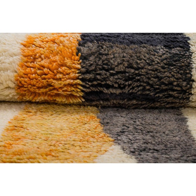 Modern hand-knotted wool rug featuring bold abstract shapes in Charcoal Black and Saffron Orange on a warm Ivory...