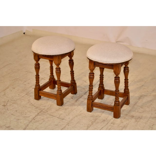 Pair of interesting Edwardian oak stools from England. The seats have been newly upholstered in linen and finished with...