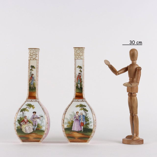 Pair of square-section porcelain vases with narrow, elongated necks. Decorations of bunches of flowers within reserves...