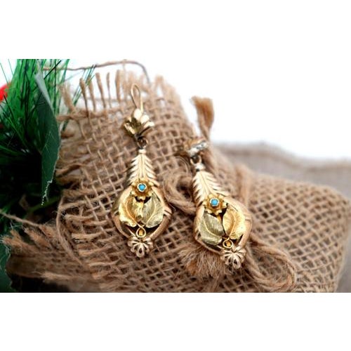 Gold earrings with applications and reliefs with blue stones inlaid in the shape of an olive leaf in a tilting manner....