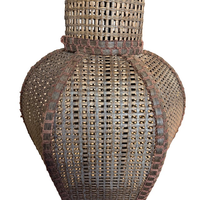 A striking large-scale vintage table lamp featuring an intricately handwoven rattan and cane body in an elegant urn-form...