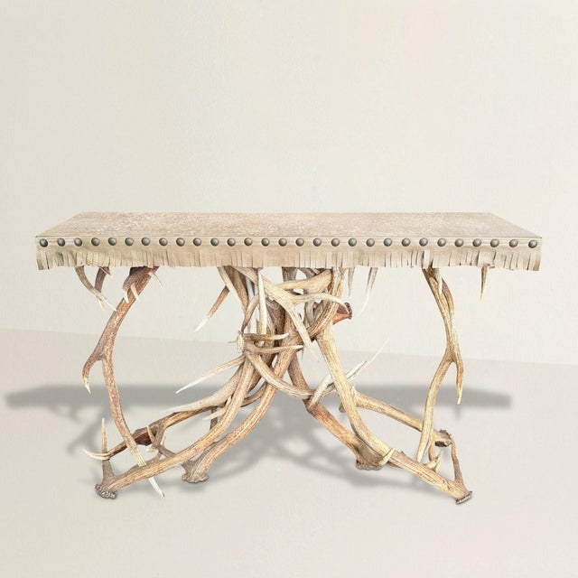 This console table lives in the tension between opposites. Its base is formed from dozens of naturally shed elk antlers,...