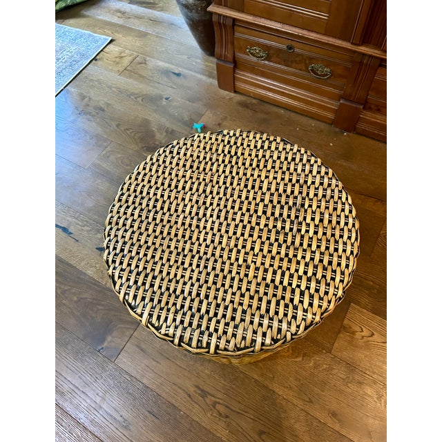 This vintage coastal woven rattan drum-shaped side table features an intricate basket weave and a round inset glass top