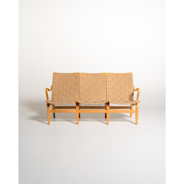Laminated and curved beech frame, with seats and backrests made of wide woven fabric straps. Original branding present....