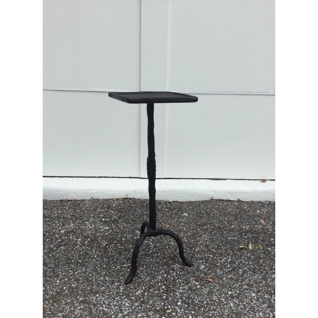 The chunky, textured tripod stand gives this square-topped drink table its slender silhouette. A laurel leaf detail in the...