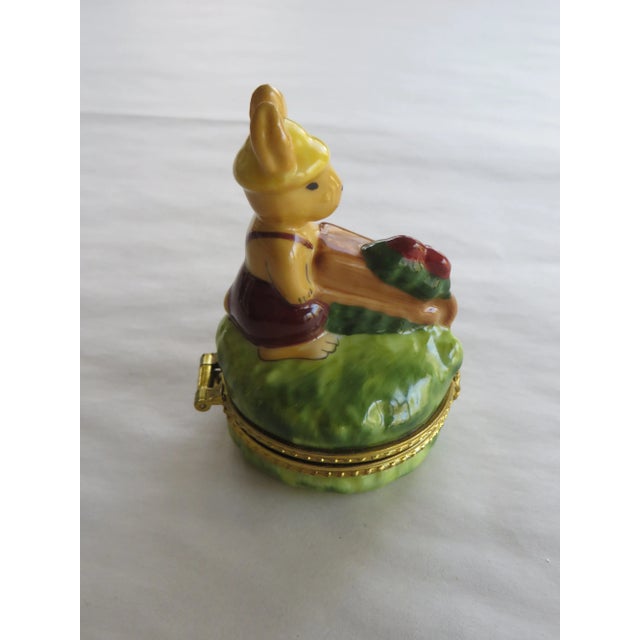 Vintage Limoges porcelain trinket box with a small rabbit pushing a wheelbarrow on the cover. Size: 2" diameter x 3.5" tall