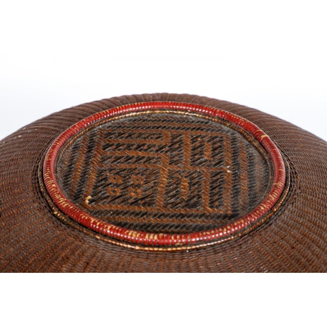 A finely woven antique Chinese reddish-brown lacquered rattan basket with a tall arched handle, lid, round body and small...