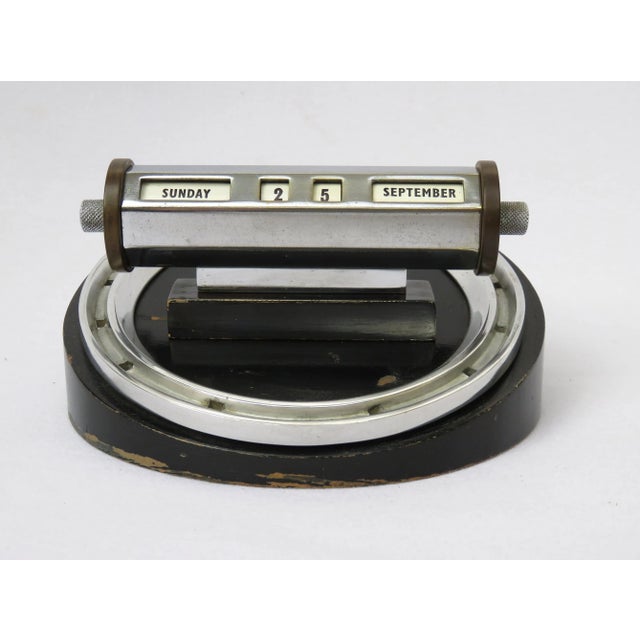 This perpetual calendar on a wooden base was made in England in the Art Deco style. The piece is painted black, and has a...