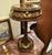 This elegant French style side table features a rich dark wood finish accented with refined gold leaf details that...