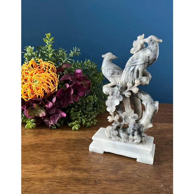 Beautiful hand-carved stone sculpture depicting two intertwined phoenix-style birds perched among branches. The carving...