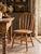 A vintage 1930s Windsor-style farmhouse chair featuring a gracefully curved bow back with five slender spindles, a shaped...