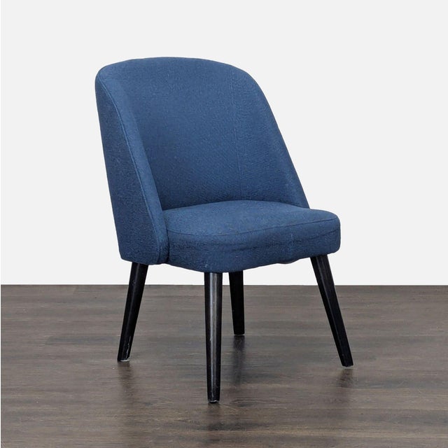 This chair with a hardwood frame features a wraparound back upholstered in welted fabric and thin tapered legs. Brand:...