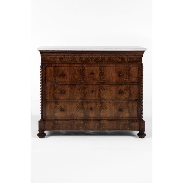 A beautiful chest of drawers or commode in flamed mahogany with a gently over sailing white marble top with rounded...