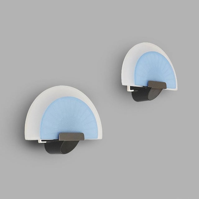 Elegant pair of wall sconces produced by Arteluce in the 1980s, designed by Ezio Didone. Structure in white and gunmetal...