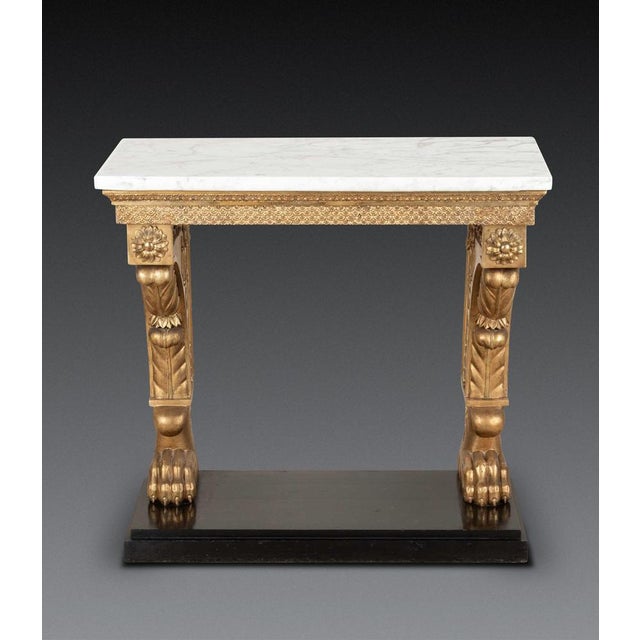 a stylish early c19th swedish console table, the original carrara marble top above a giltwood base with carved acanthus...