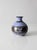 A vintage handmade studio pottery vase featuring a lavender blue glaze, earthy brown banding, and hand-decorated floral...