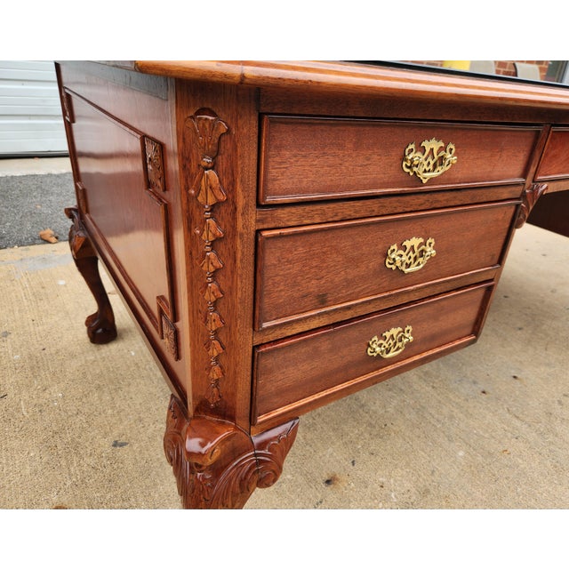 Traditional Chippendale-style executive desk, with richly carved cabriole legs and ball-and-claw feet giving it a formal...