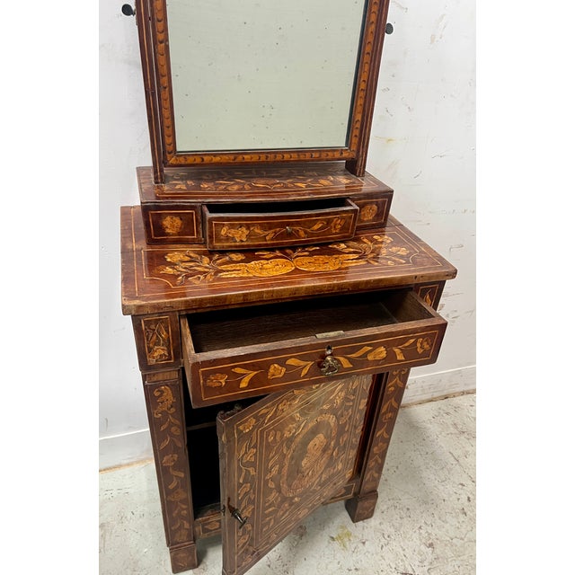 Dutch marquetry dressing table Low cabinet opening with a front door decorated with foliage and a bust of a figure The...