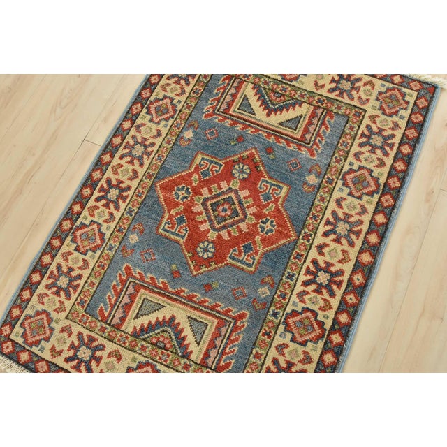 A tribal Caucasian Kazak rug hand-knotted with an all-wool pile on a cotton foundation. This oriental rug features a...