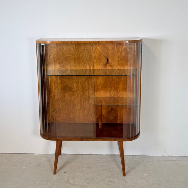 This distinctive 1950s display cabinet, originating from Poland, immediately catches the eye with its elegant curved Art...