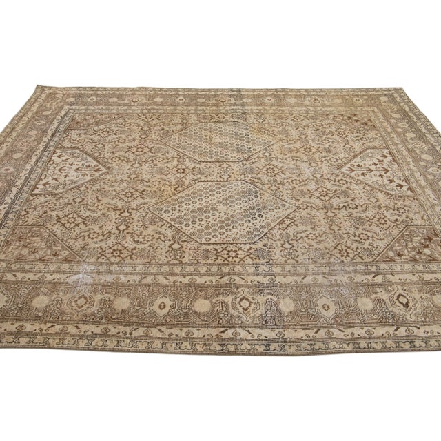 Beautiful antique Persian distressed hand-knotted wool rug with a brown and beige color field. This piece has a designed...