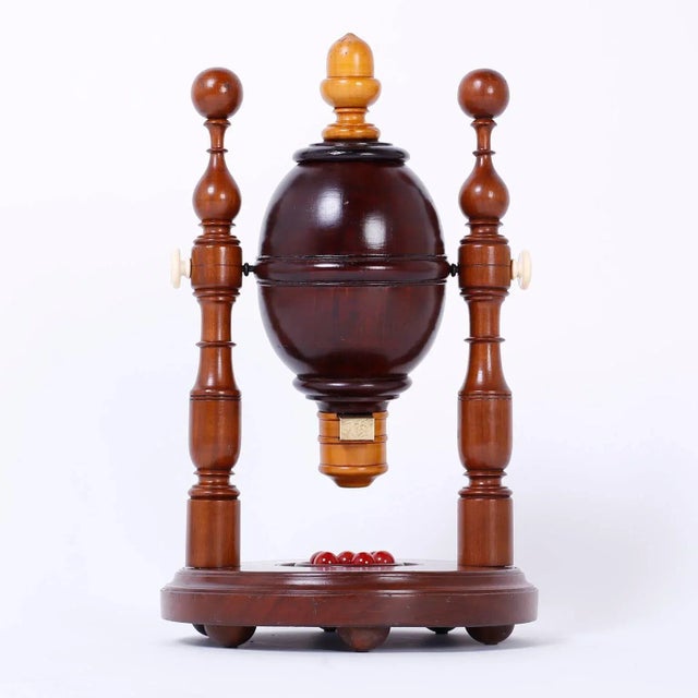 Curious mechanical lottery apperatice that has a hardwood spinning canister with pine cap and spout, supported by two...