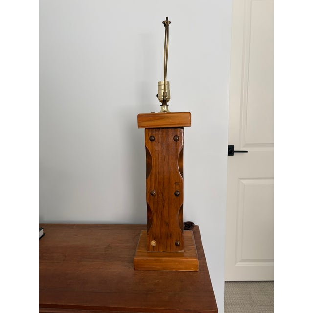Great vintage rustic table lamp with a sculpted pine column body, decorative brass nailhead studs, and carved diamond...