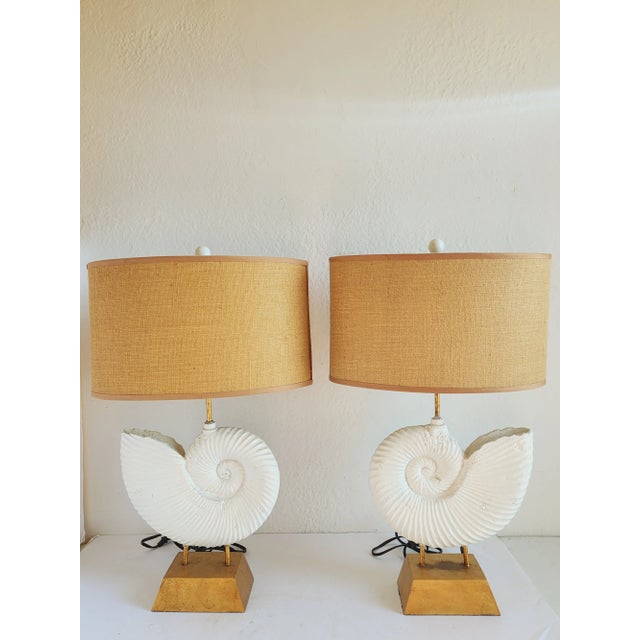 Stunning fossilized ammonite motif table lamps with gilt metal finish and oval burlap shades. The lamps will fit in many...