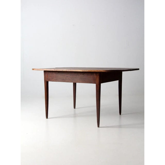 An antique wooden table with a seldom found two-plank top. Its tapered legs offer. a simple, well-proportioned form. The...