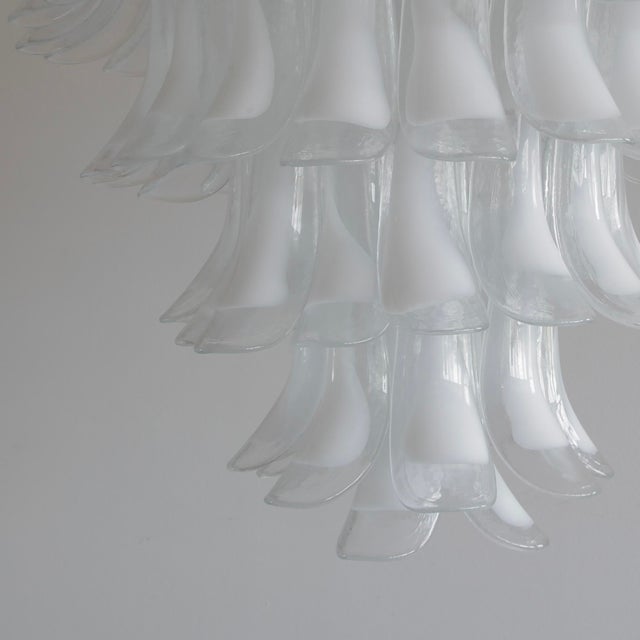 A very large chandelier with a white painted steel frame and well over 130 hand-blown 'saddle form' glass pieces. Clear...