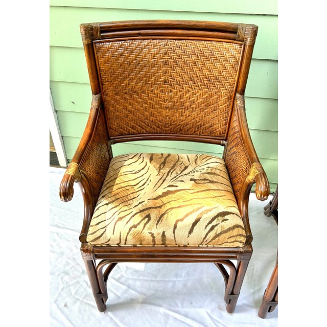 A stylish pair of vintage bamboo and rattan armchairs featuring woven wicker backs and sculptural bent bamboo frames....
