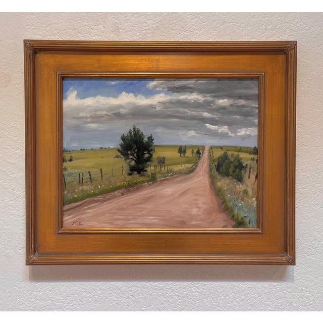 This oil on board painting captures a winding dirt road that stretches into a vast landscape, flanked by gentle hills and...