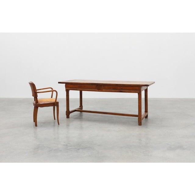 A handsome French oak dining table dating from around 1830, showcasing the timeless appeal of rural craftsmanship. The...