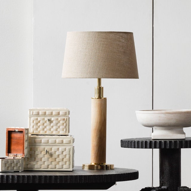 New Item. Sporting a natural wood pillar that is supported by an antique brass base and frame, the Lena Table Lamp is an...